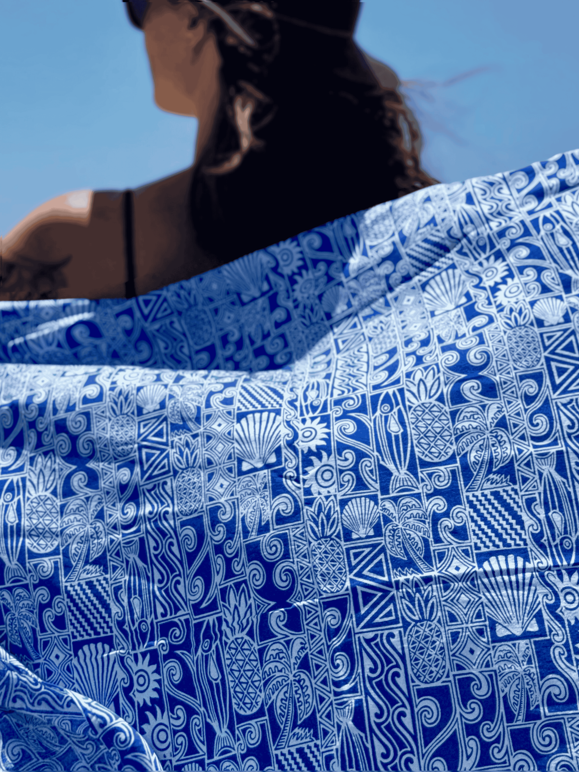 Person holding a blue and white patterned sarong with a clear blue sky in the background
