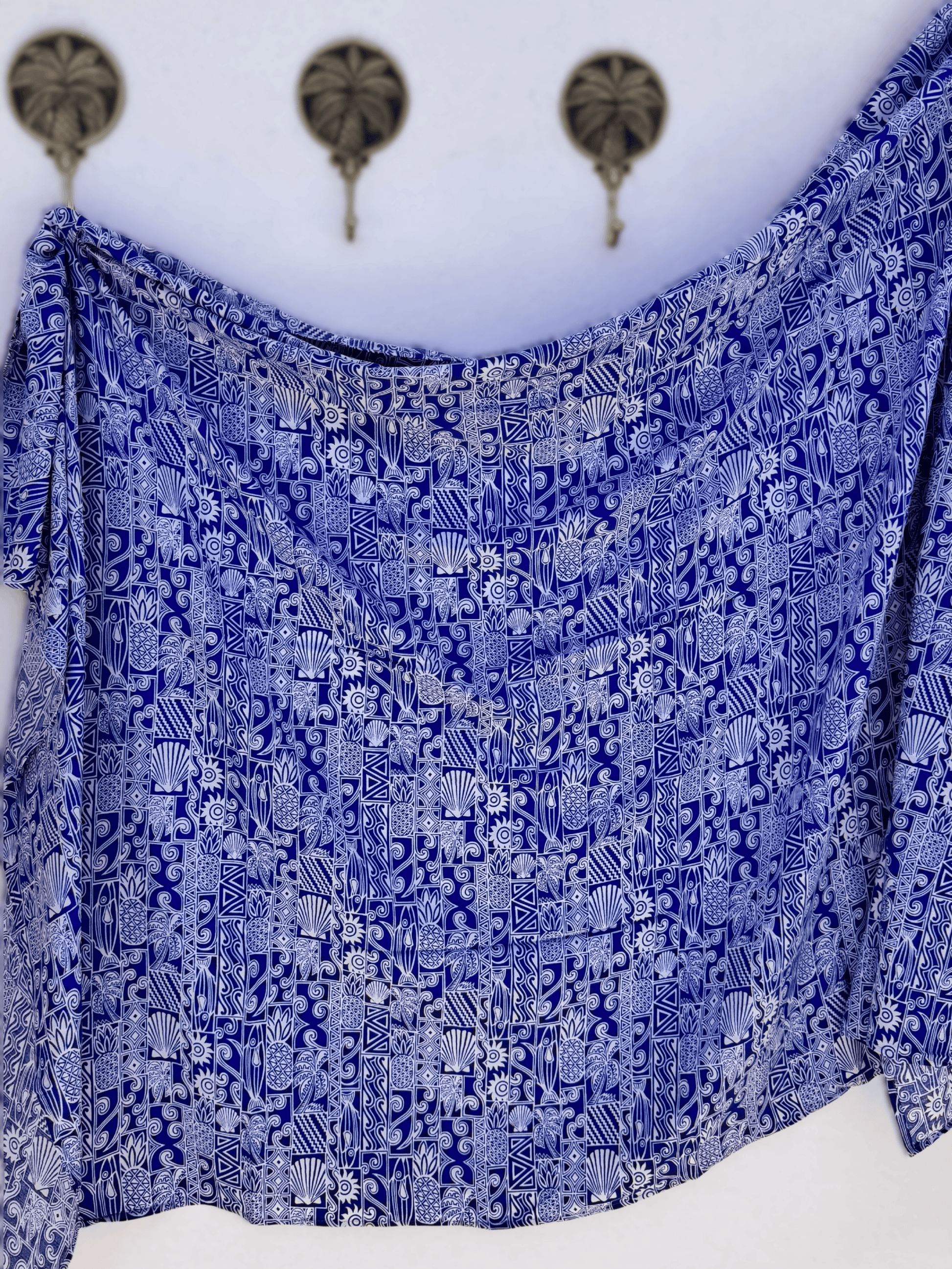Blue patterned Sarong draped over a white surface with decorative elements in the background.
