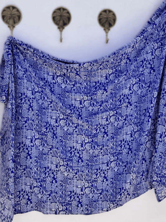 Blue patterned Sarong draped over a white surface with decorative elements in the background.