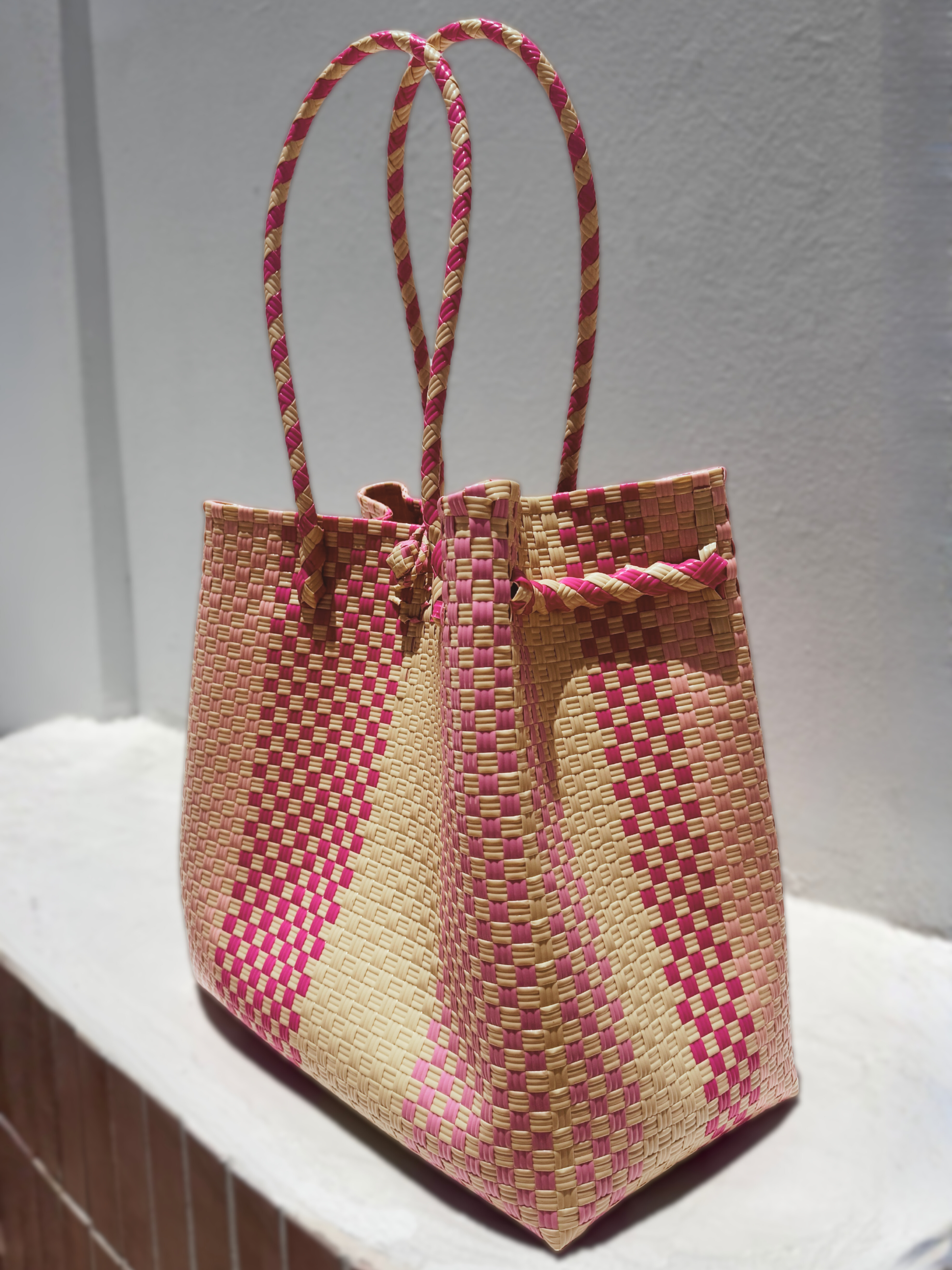 Woven bag with pink and beige pattern on a white surface