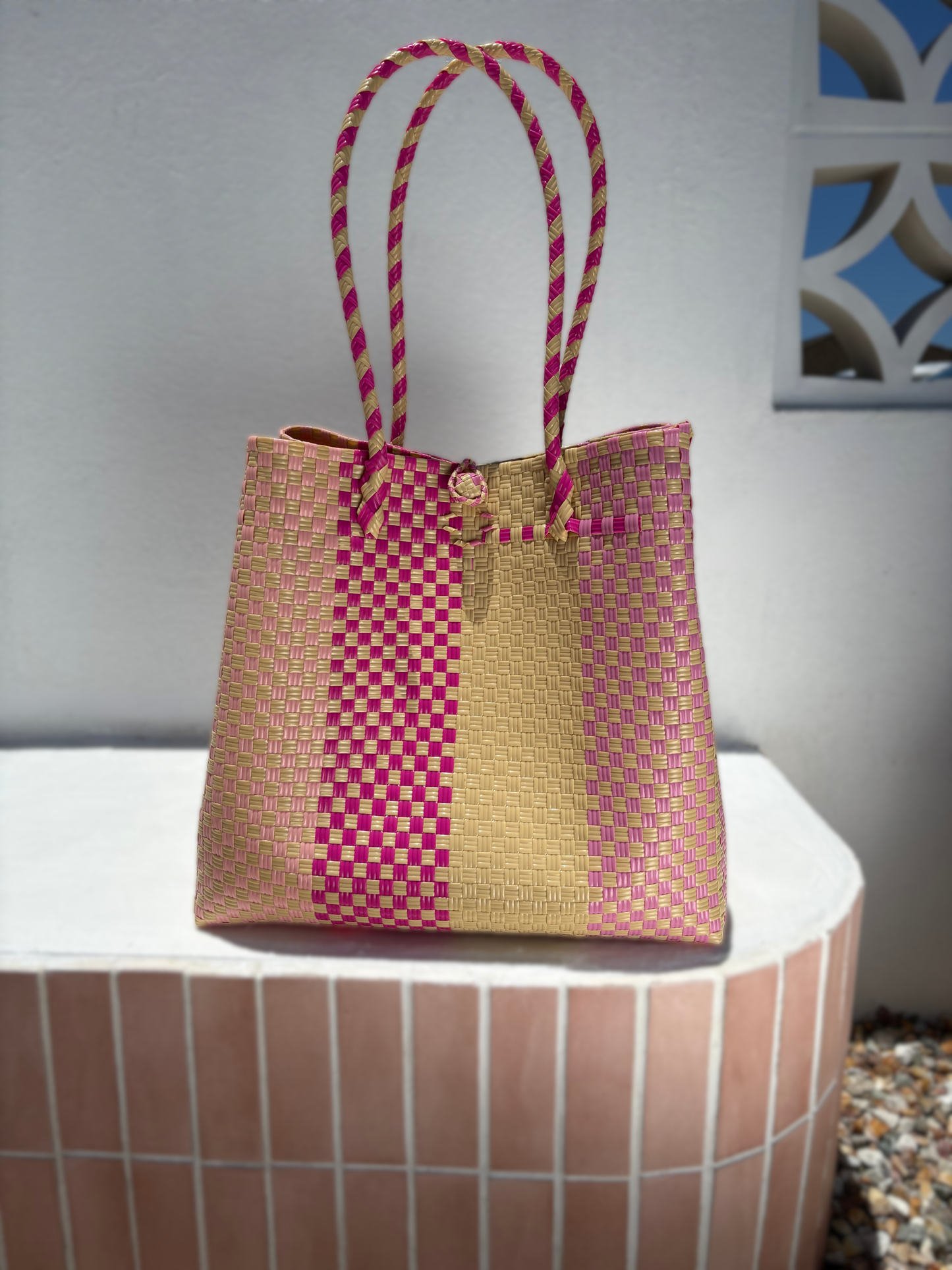 Woven handbag with pink and cream pattern on a white surface