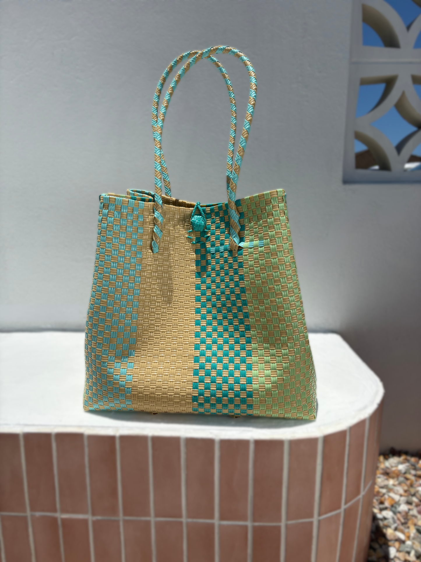 Woven handbag with green and beige pattern on a white surface