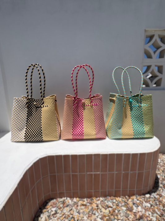 Three woven bags with different color patterns on a ledge.