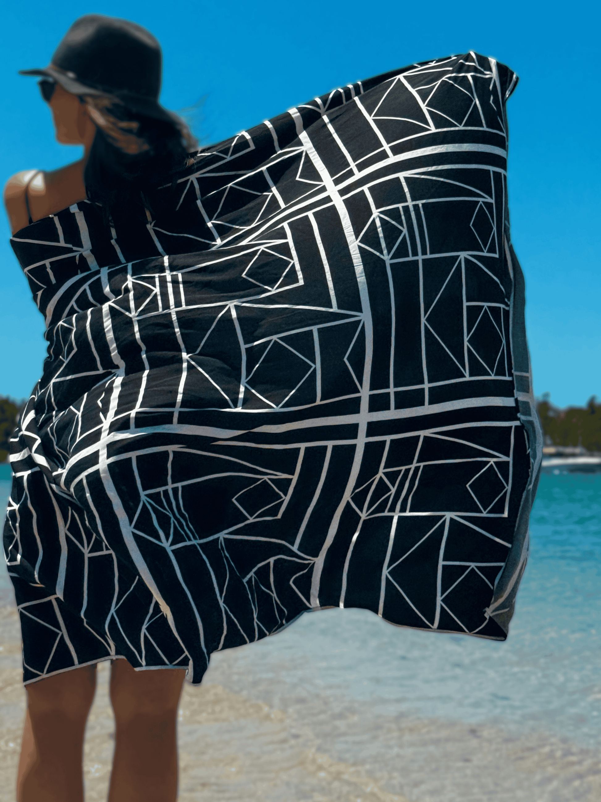 Person wrapped in a black and white patterned sarong on a beach