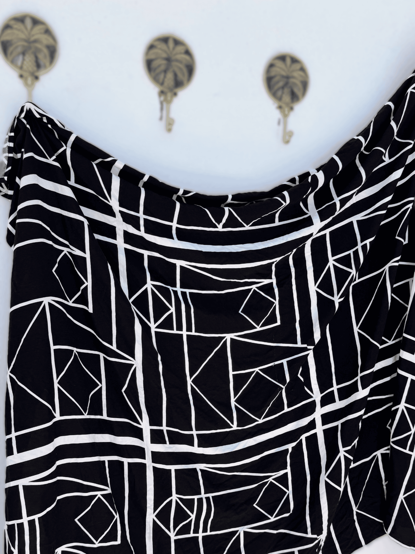 Black and white geometric patterned sarong on a white background with decorative elements.