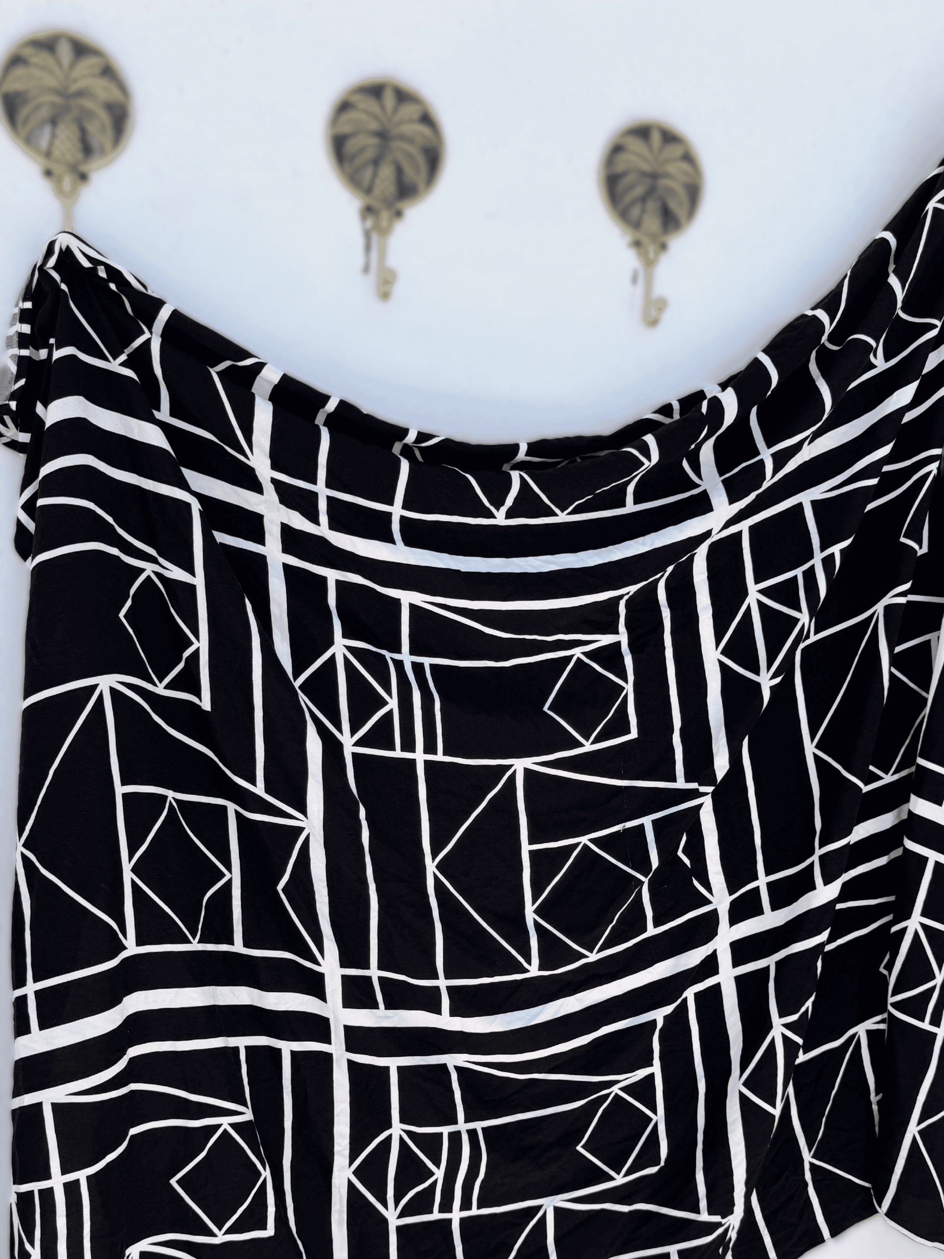 Black and white geometric patterned sarong on a white background with decorative elements.