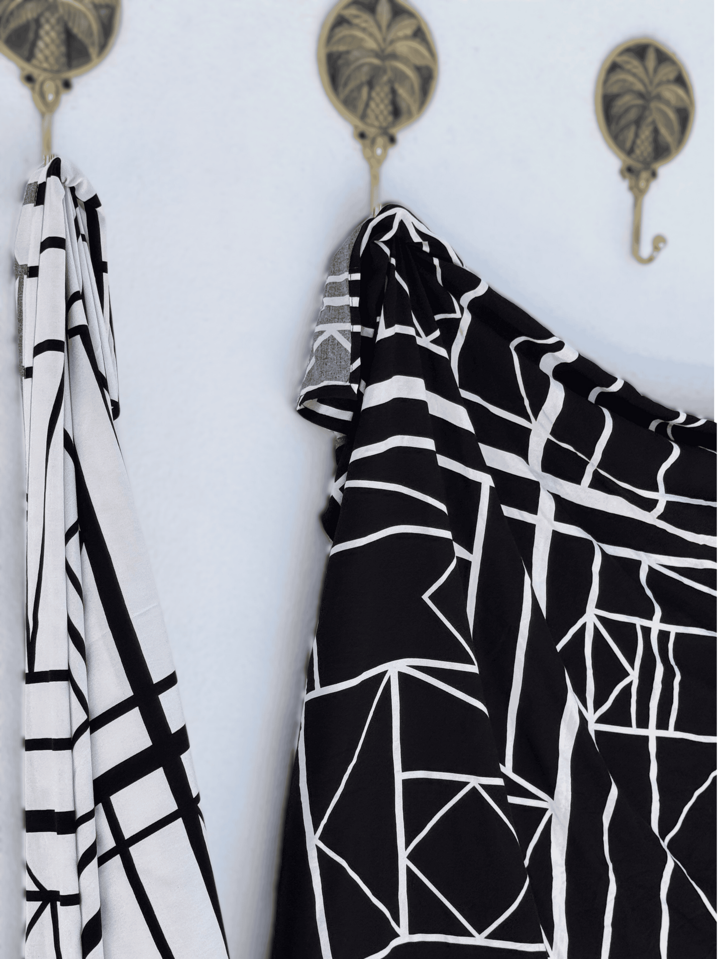 Black and white patterned sarong hanging on a wall with decorative hooks.