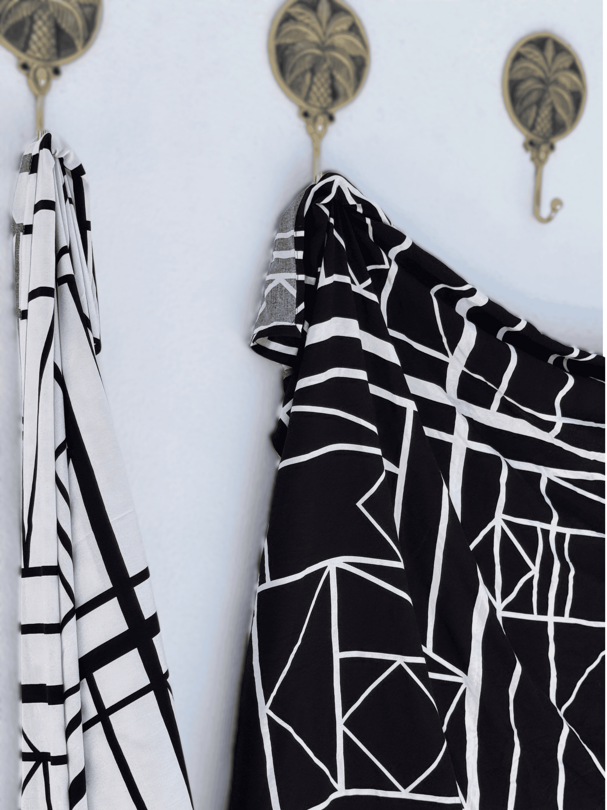 Black and white patterned sarong hanging on a wall with decorative hooks.