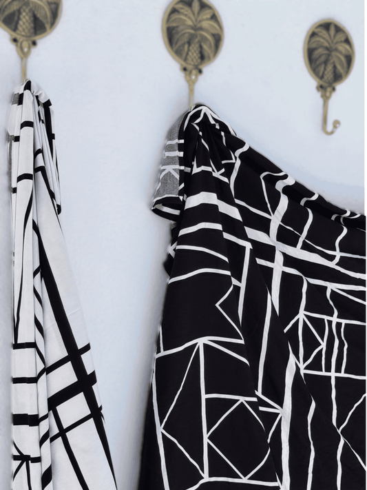 Black and white patterned sarong hanging on a wall with decorative hooks.