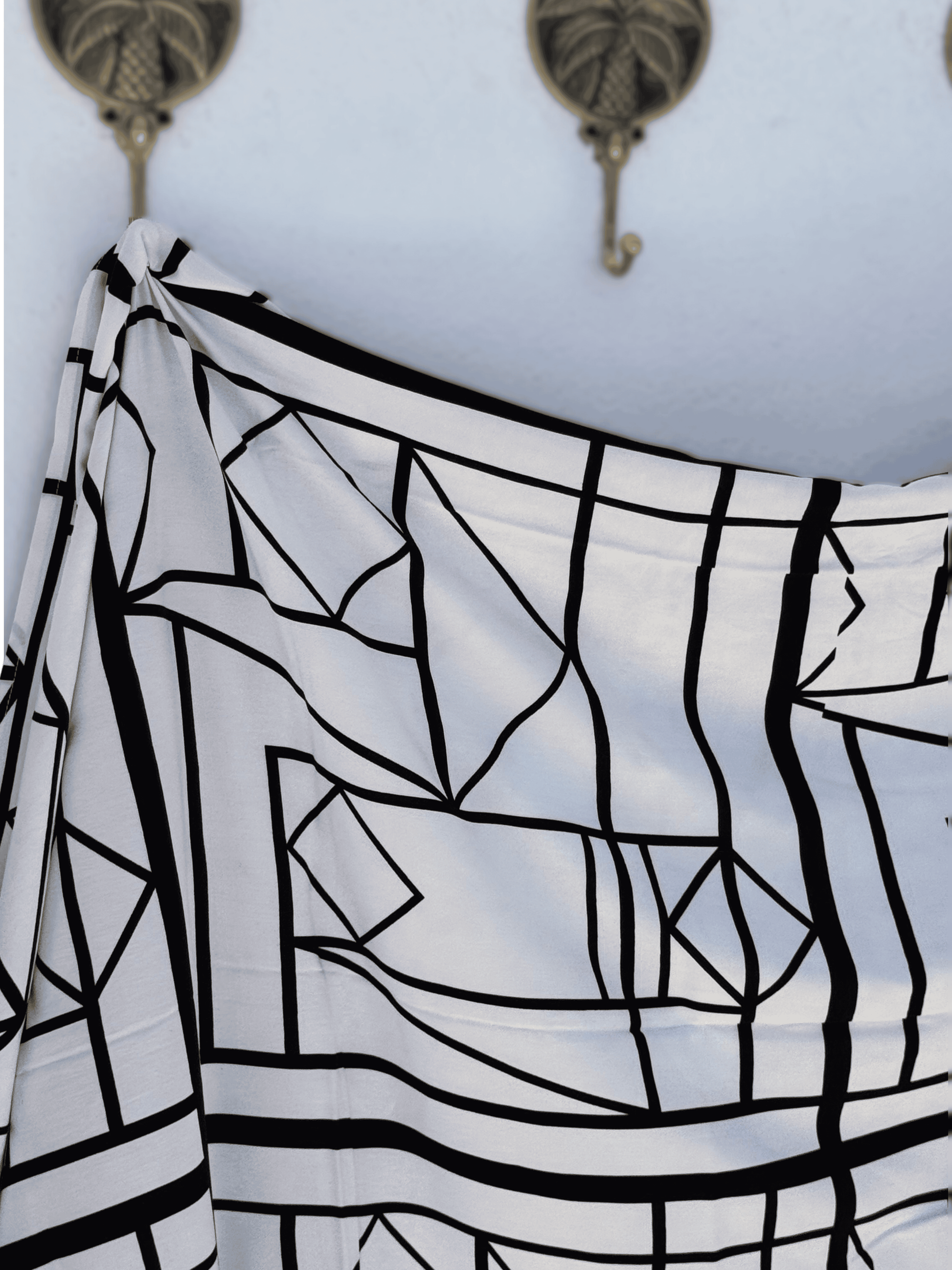 Black and white patterned sarong draped over a surface with hooks in the background.